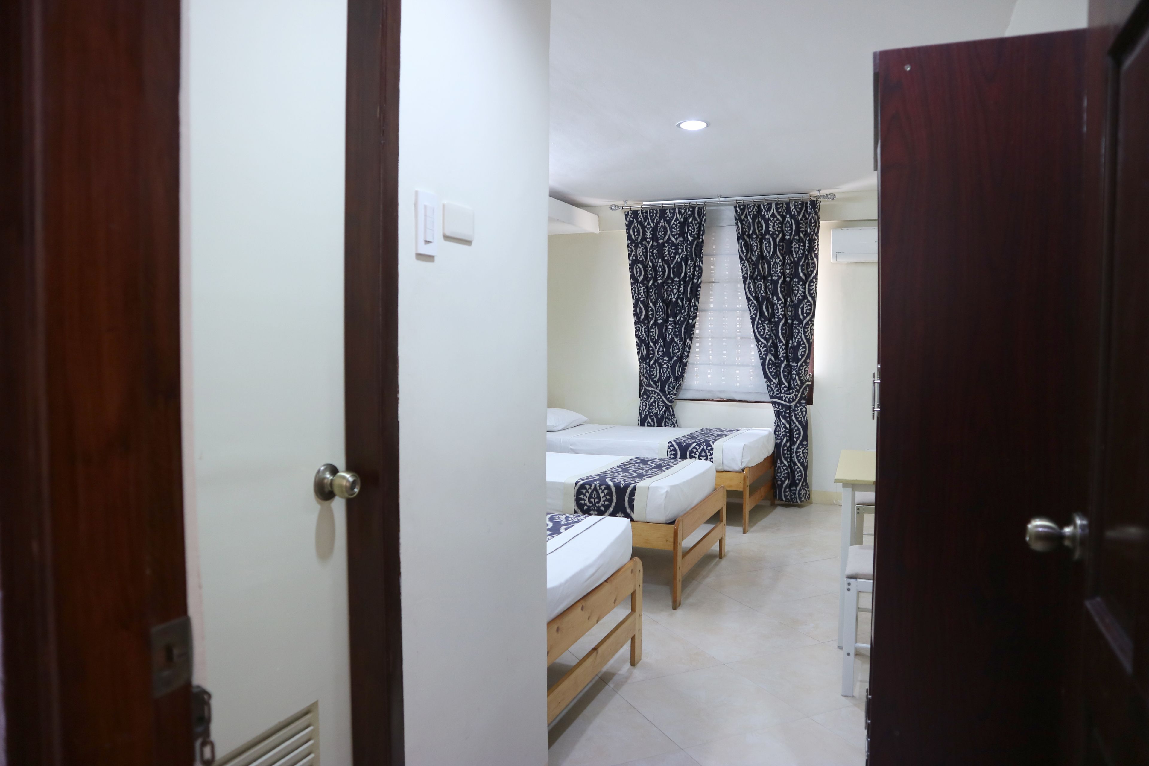 A room with two single beds, a small table, and a chair.
