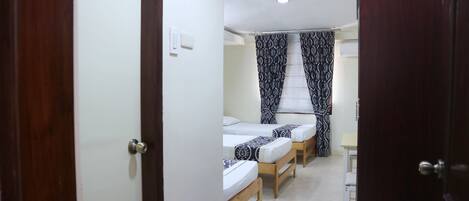 A room with two single beds, a small table, and a chair.