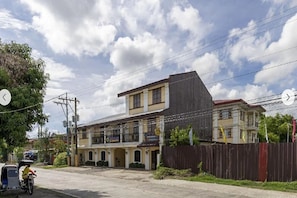 A two-story building with a flat roof and a balcony on the second floor.