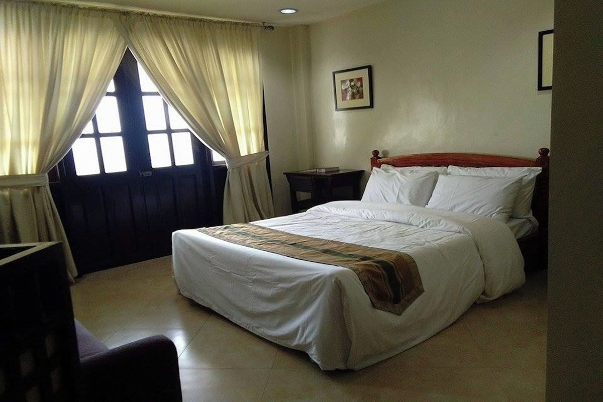 A neatly made bed with white linens, a wooden headboard, and a small bedside table.