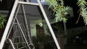 A swing set in a garden area with bamboo plants and a building in the background. - Thisara Guest Hotel Rooms (Kataragama)