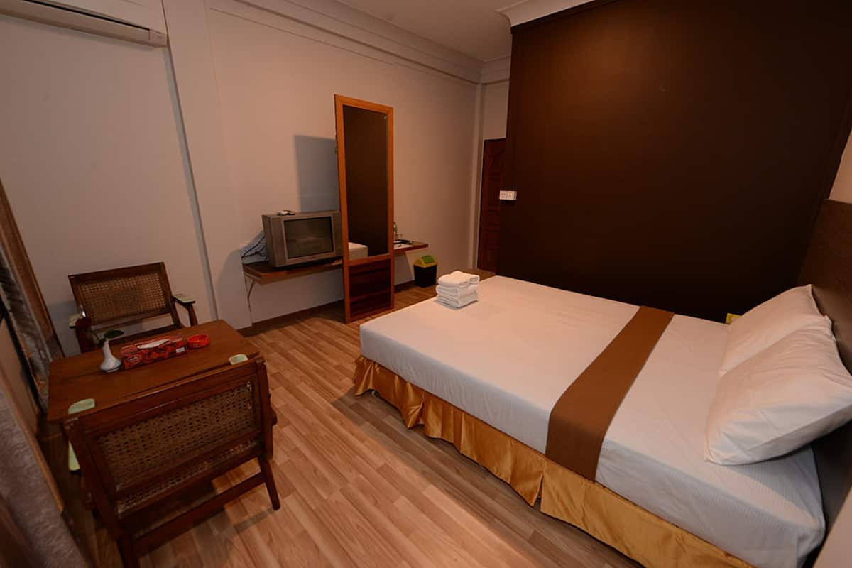 Hotellihuone, jossa on sänky, työpöytä, tuoli, televisio ja peili.