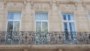 Une façade d’immeuble avec trois fenêtres et des balcons en fer forgé décoratifs.