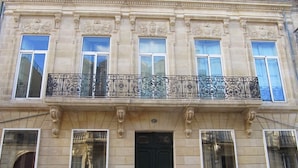 Un bâtiment doté d’une porte noire, de nombreuses fenêtres et d’un balcon orné de balustrades en fer forgé.