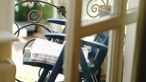 Ein Balkon mit Metallgeländer, einem Blumentopf und einem Stuhl mit Blumenkissen.