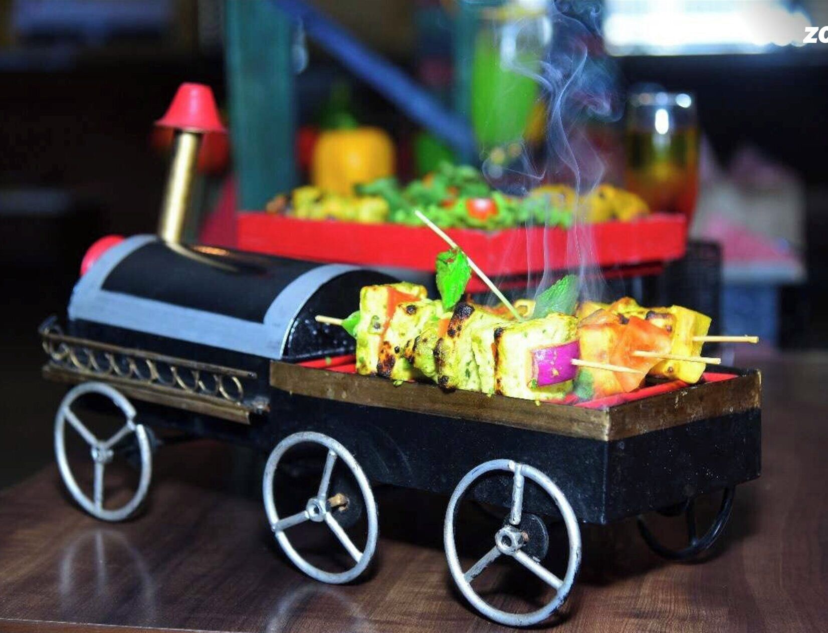 A miniature train with a grill cart carrying skewers of food.