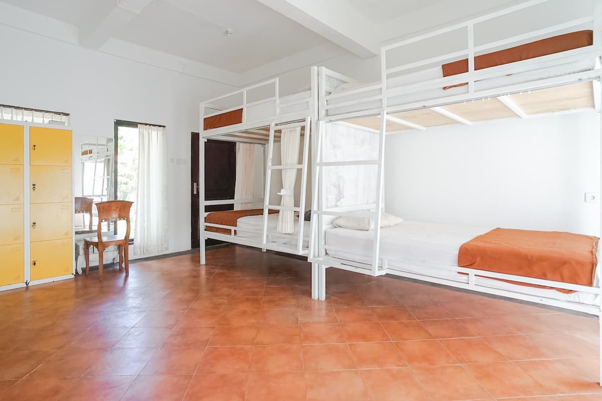 A dormitory room with bunk beds, a wooden chair, and a yellow wardrobe.