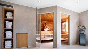 A modern bathroom with a glass shower enclosure, wooden benches, and a towel rack. - Gut Heckenhof Hotel & Golfresort (Eitorf)