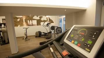 Un gimnàs amb cinta de córrer, bicicleta estatica i banc de musculació.