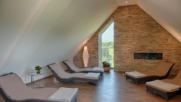 Relax by the fireplace in a cozy seating area with lounge chairs and a potted plant.