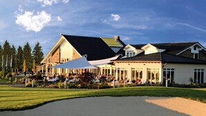 A golf course with a clubhouse and dining area. - Gut Heckenhof Hotel & Golfresort (Eitorf)