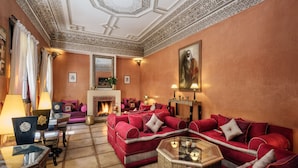 A spacious living room with a fireplace, red sofas, and a large mirror. - Riad Dar El Souk (Marrakech)
