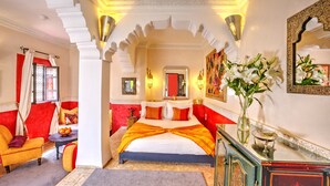 A traditional room with a bed, a sofa, a small table with fruit, and a vase with flowers. - Riad Dar El Souk (Marrakech)