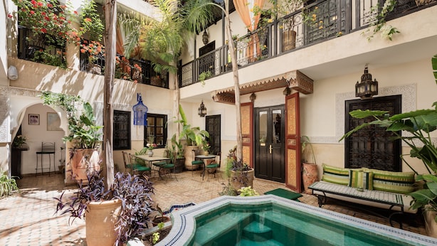 A courtyard with a pool, potted plants, outdoor furniture, and a balcony with plants. - Riad Dar El Souk (Marrakech)