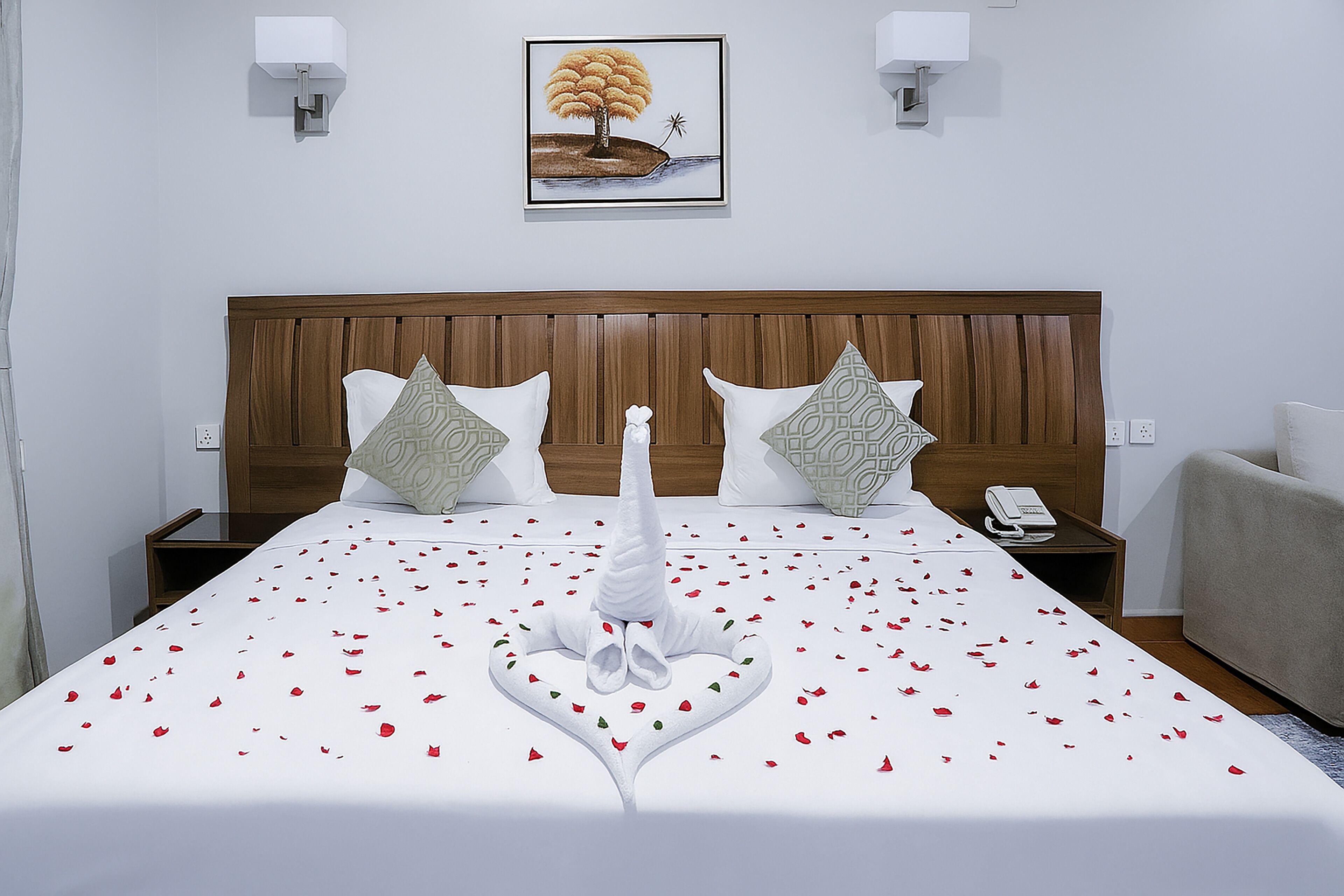 A hotel room with a large bed, two nightstands, a telephone, and a framed picture on the wall.