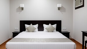 A neatly made bed with a patterned bedspread and two pillows, flanked by nightstands with wall-mounted lamps. - Al Mawasim Al Arbaeah Serviced Apartments (Tabuk)