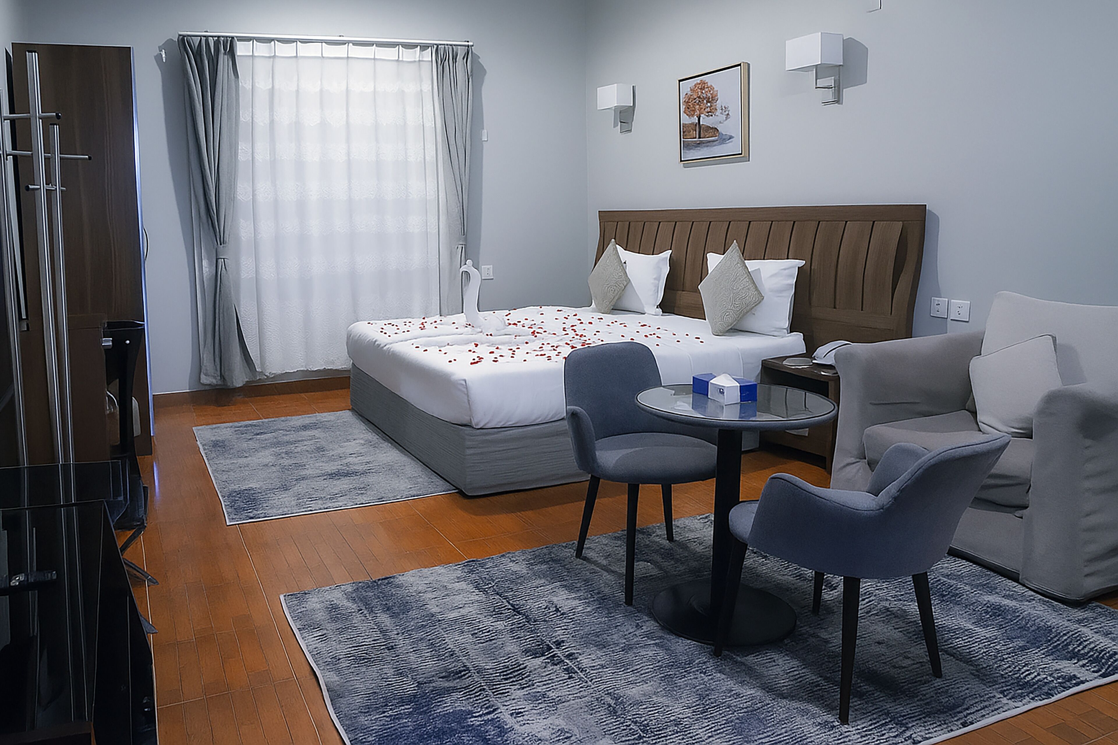 A hotel room with a bed, a sofa, a chair, a small table, and a window with curtains.