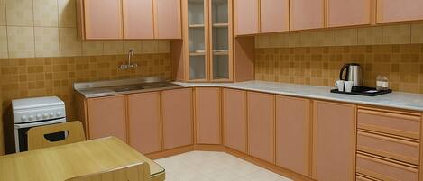 Una cocina con armarios de madera, una estufa blanca y una encimera con una cafetera y botellas de agua.