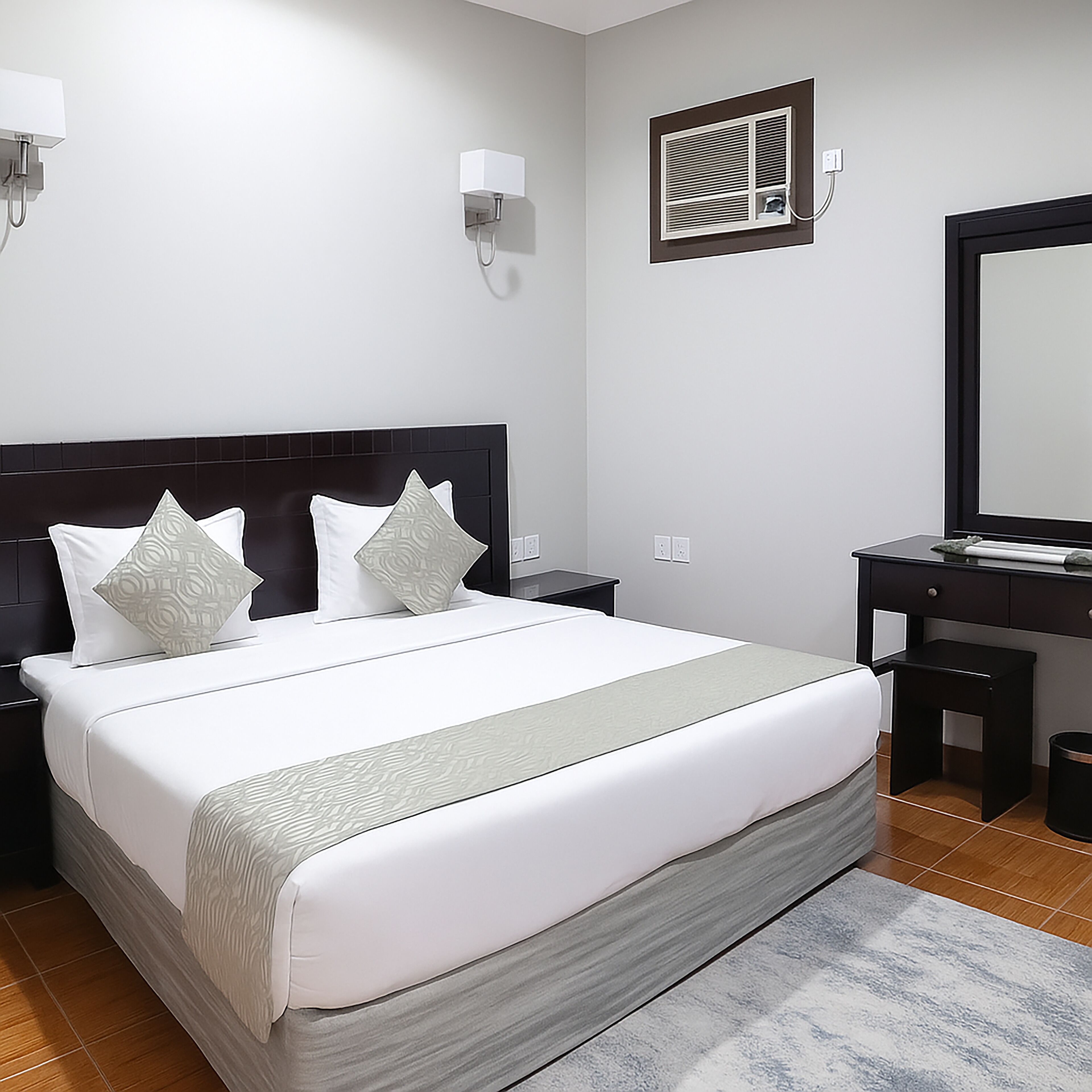 A neatly arranged hotel room with a large bed, a desk, and a mirror.