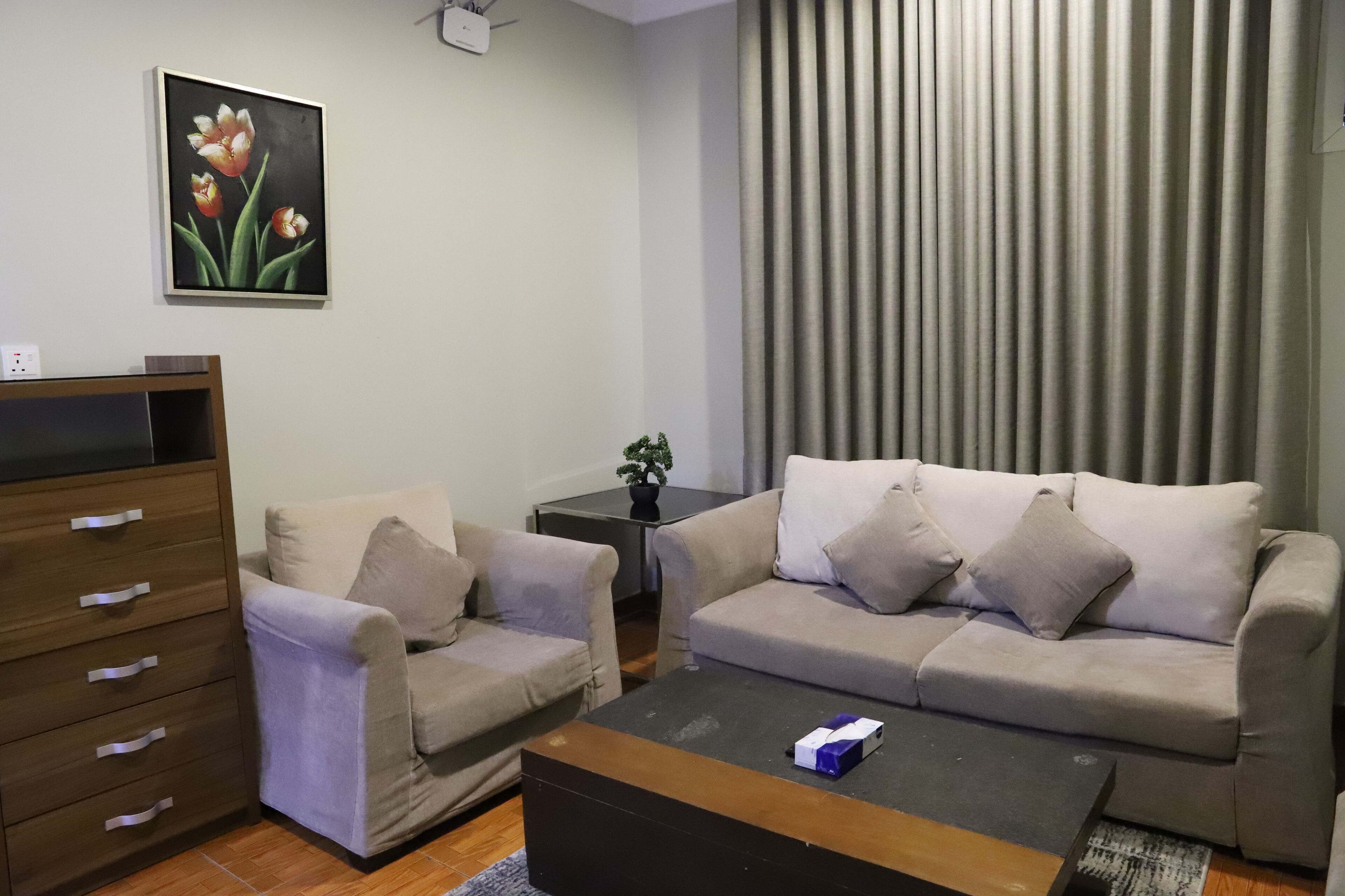 A living room with a sofa, a coffee table, a TV stand, and a painting on the wall.