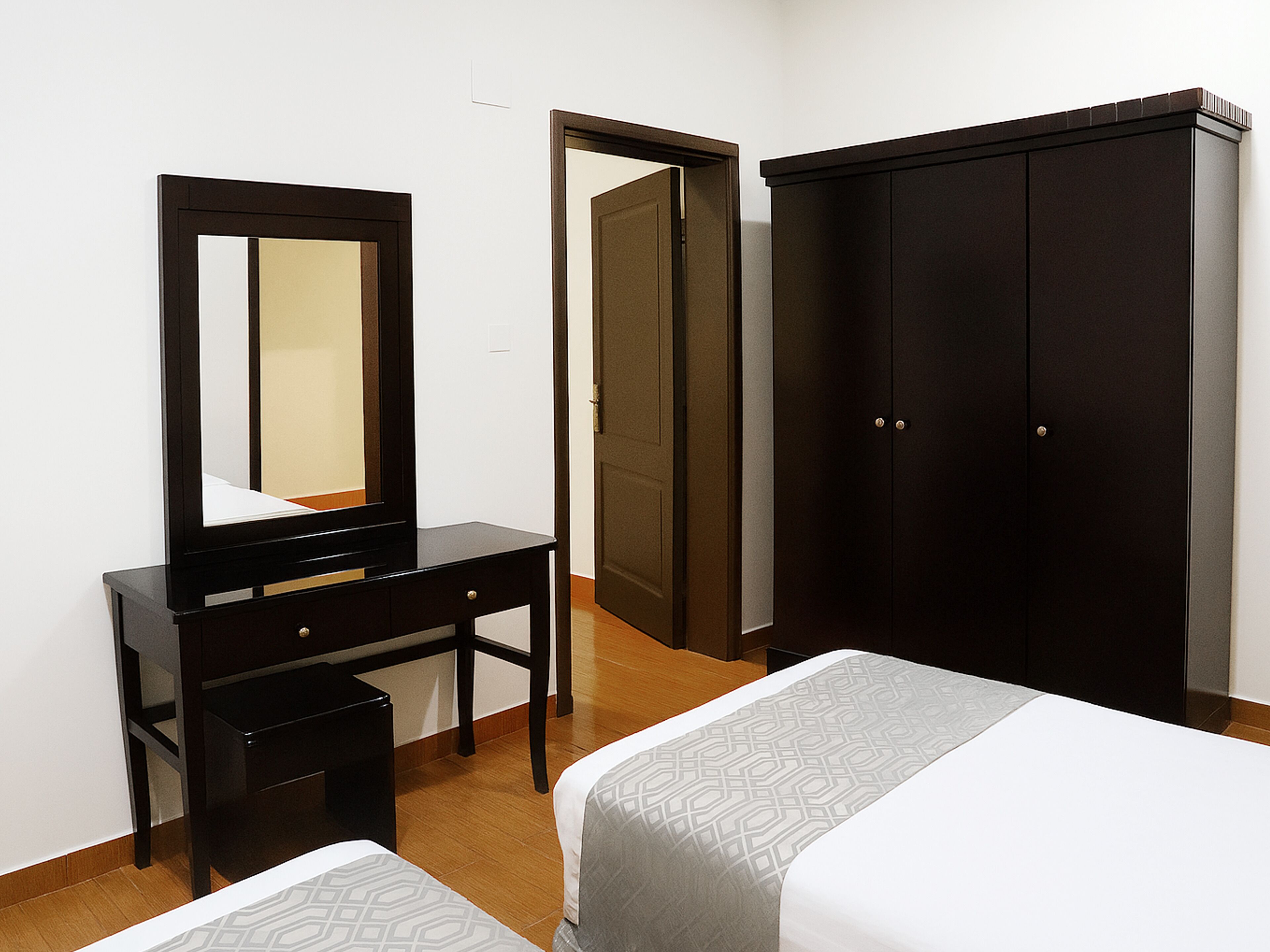 A bedroom with a bed, a dresser, a mirror, and a wardrobe.