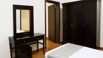A bedroom with a bed, a dresser, a mirror, and a wardrobe.