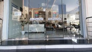 A hotel entrance with glass doors and a motorized awning. - Al Mawasim Al Arbaeah Serviced Apartments (Tabuk)