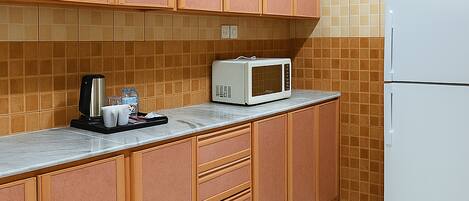 A kitchen with wooden cabinets, a microwave, a refrigerator, and a tiled backsplash.