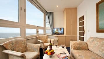 Suite, balcón, vistas parciales al mar | Sala de estar | Una televisión de pantalla plana
