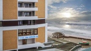 Un hotel con un cartel que dice "Hotel Monbijou" con vista a una playa y un barco fondeado cerca.