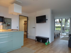Una cocina moderna con una isla integrada, una zona de comedor con banco, y un televisor montado en la pared.