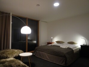Ett modernt sovrum med en stor säng, ett runt bord och en golvlampa.