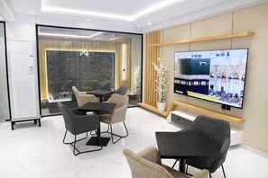 Ein moderner Konferenzraum mit einem großen Flachbildfernseher, bequemen Sitzgelegenheiten und einer Wand aus Stein als Hintergrund.