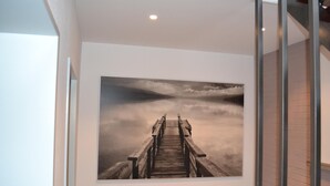 A hallway with a large framed photograph of a wooden pier extending into a misty landscape.