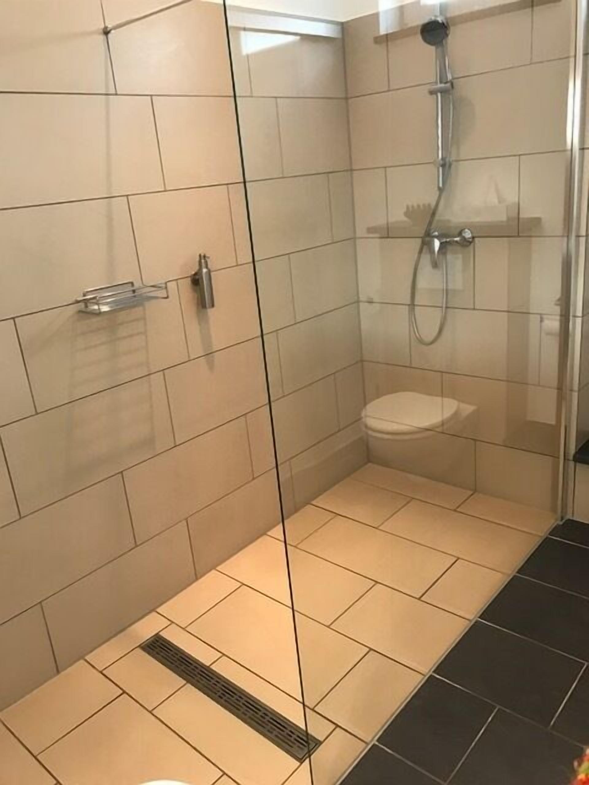 Une salle de bain moderne avec une douche à parois de verre, des toilettes et un lavabo.