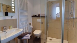 A bathroom with a sink, toilet, and glass-enclosed shower area. - Campus Boardinghouse Aachen (Aachen)