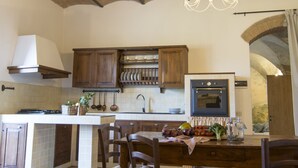 A kitchen with a central island, wooden cabinets, and a hanging light fixture. - Croce di Bibbiano (Colle di Val d'Elsa)