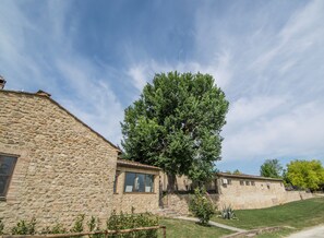 A stone building with a large tree in front. - Croce di Bibbiano (Colle di Val d'Elsa)