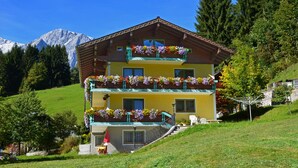 A multi-story building with balconies adorned with flowers, set against a mountainous backdrop. - Haus Elisabeth (Muehlbach Am Hochkoenig)