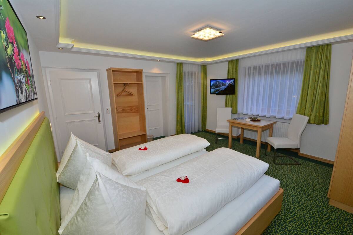 Habitación de hotel con dos camas, televisión, escritorio y una silla.