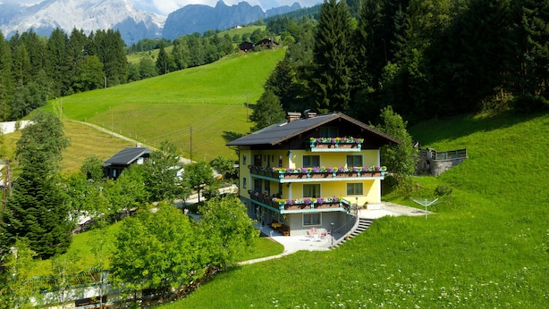 A multi-story chalet with a balcony, surrounded by lush greenery and mountains in the background. - Haus Elisabeth (Muehlbach Am Hochkoenig)