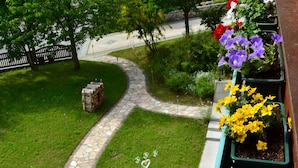 A stone pathway curving through a well-maintained lawn with flower planters on one side. - Haus Elisabeth (Muehlbach Am Hochkoenig)