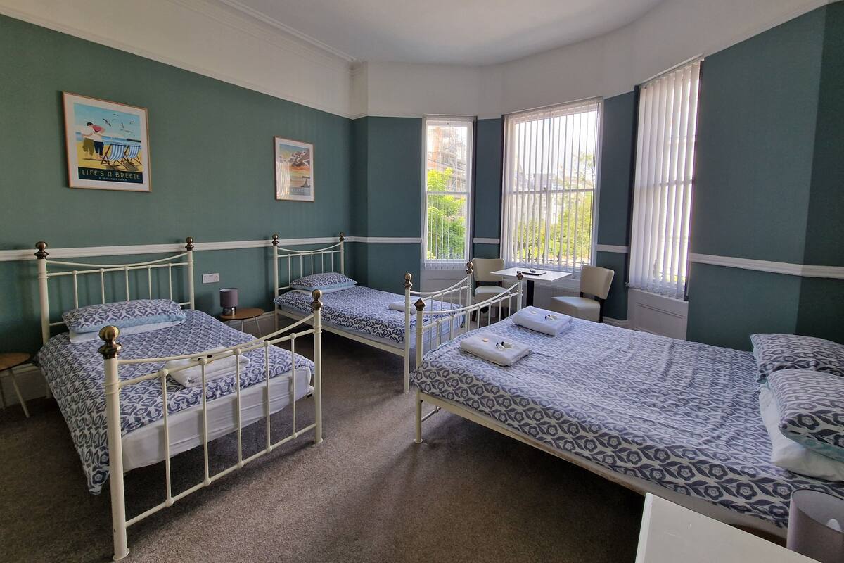 A room with three single beds, a small table, and two chairs.