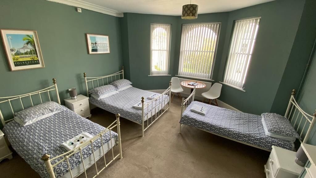A room with three single beds, a small round table, and two chairs.