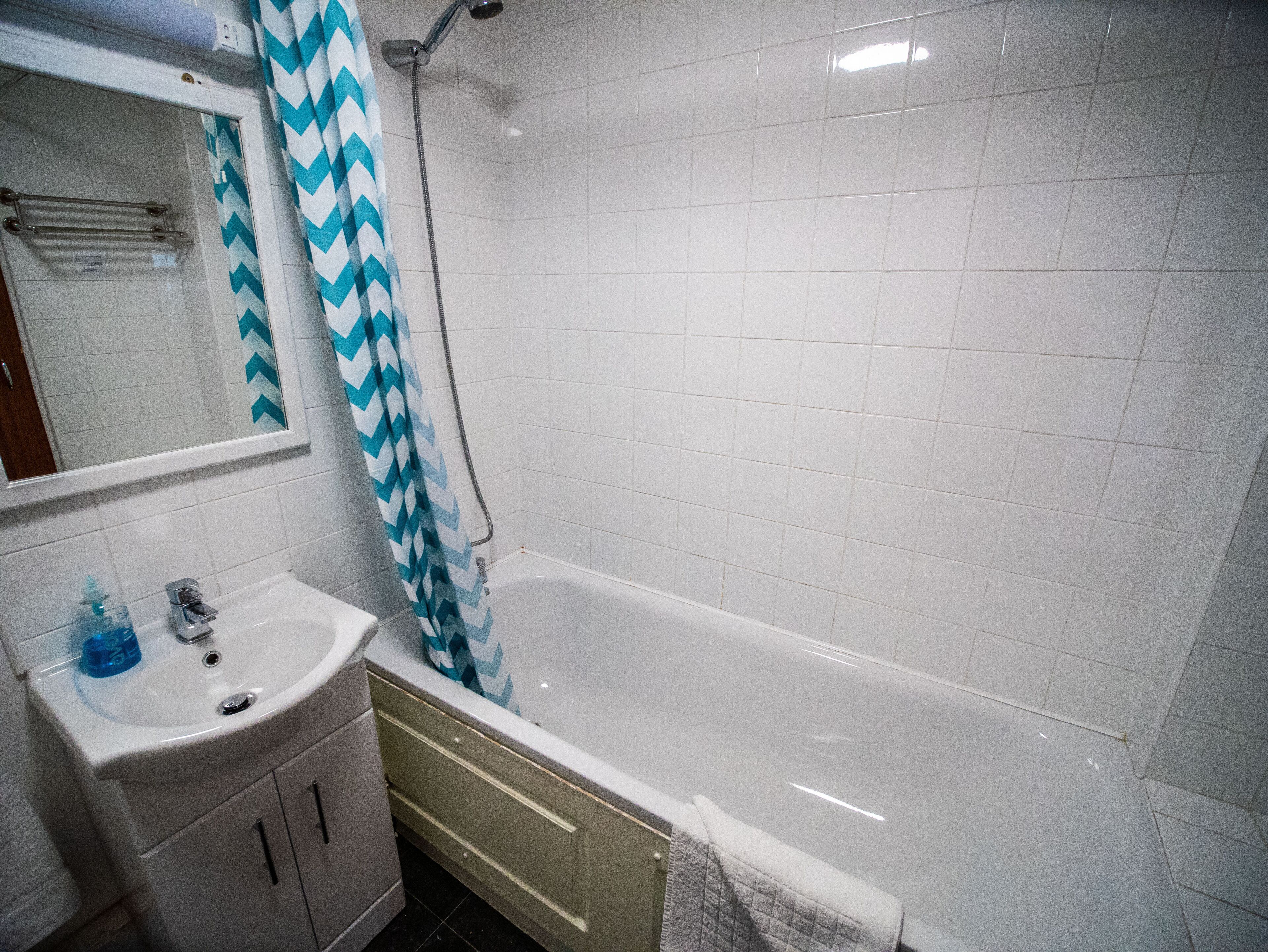 Une salle de bain avec un lavabo blanc, un miroir et une douche.
