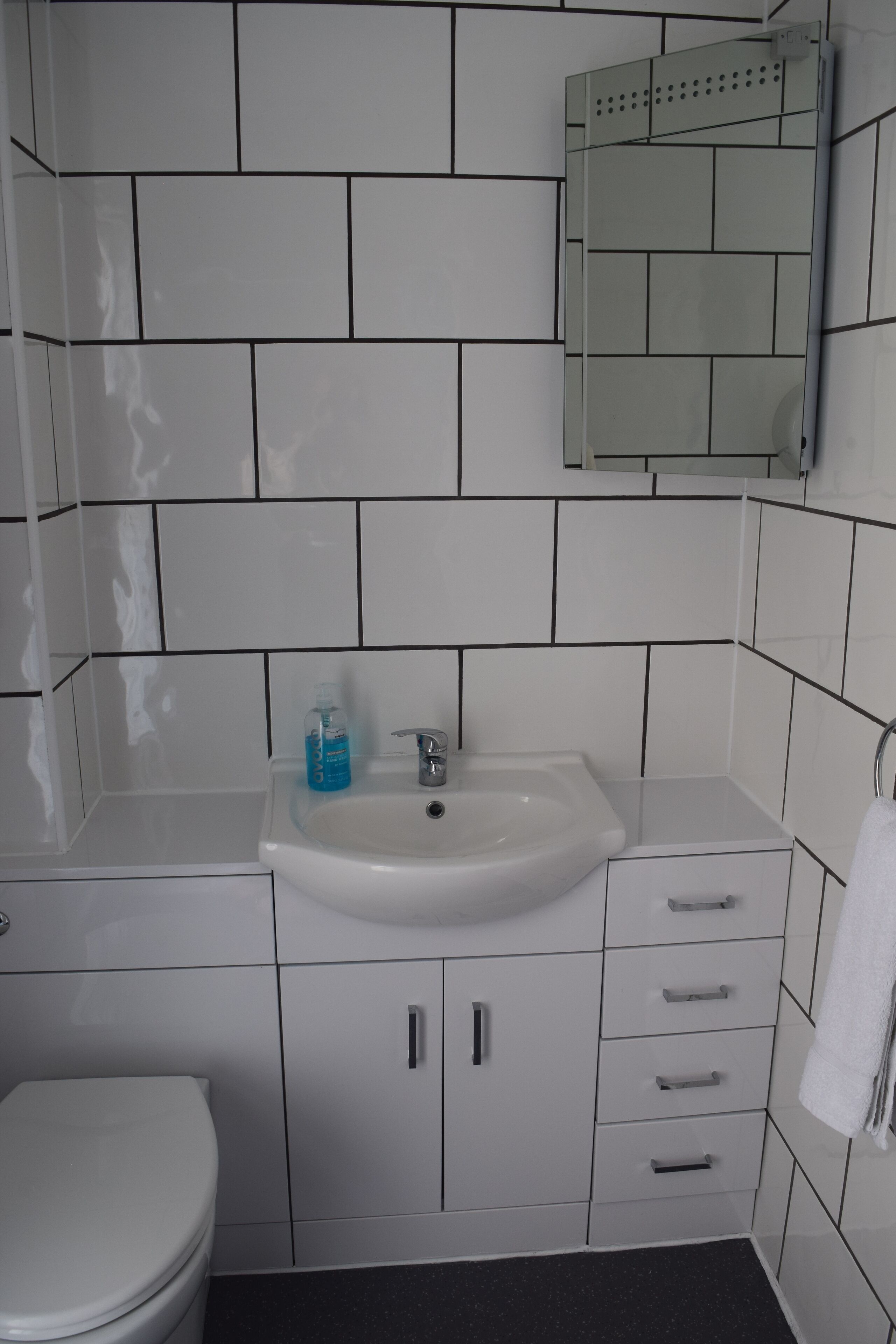 A bathroom with a white sink, mirror, and toilet.