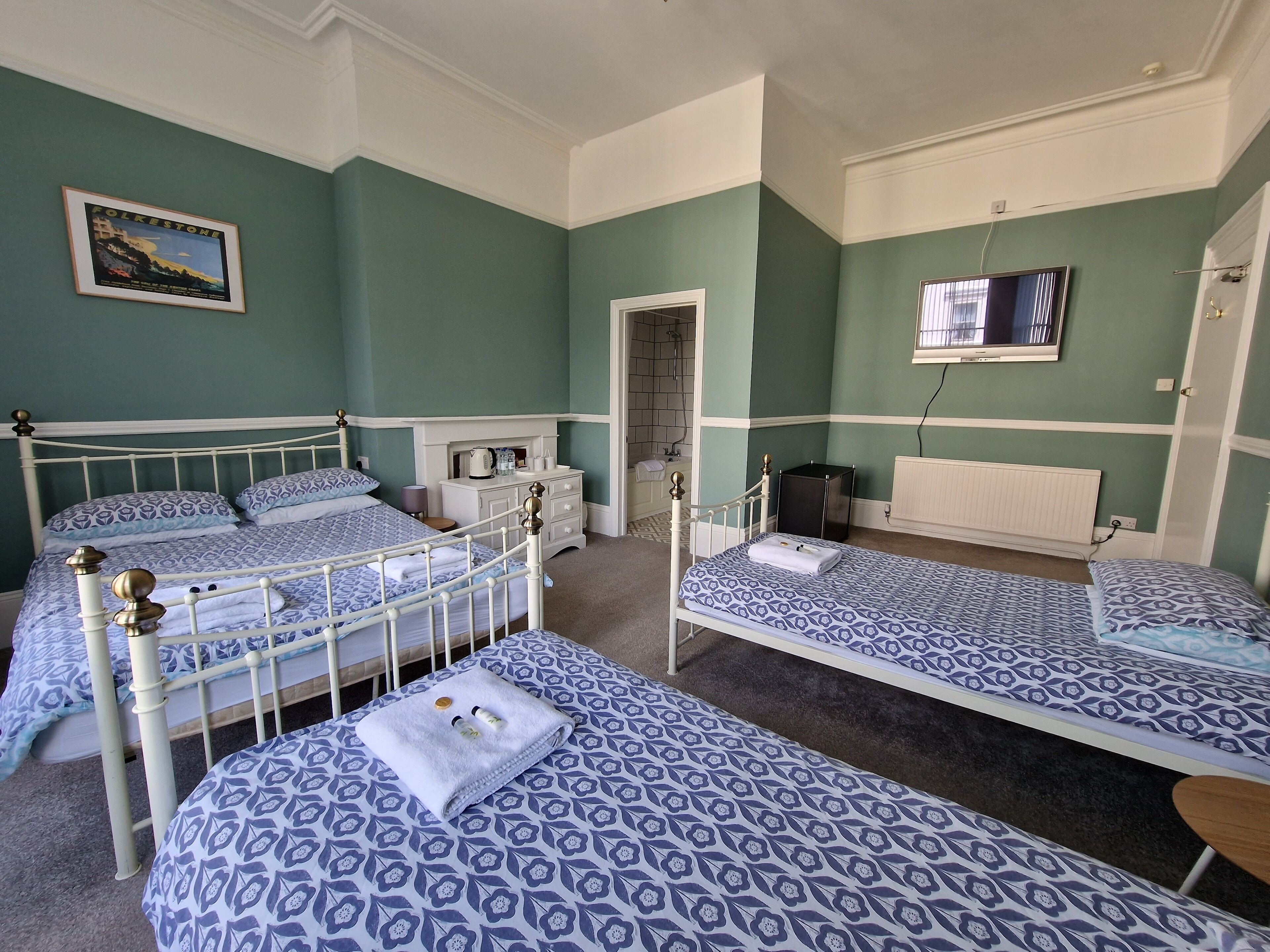 A room with two beds, a television, and a framed picture on the wall.