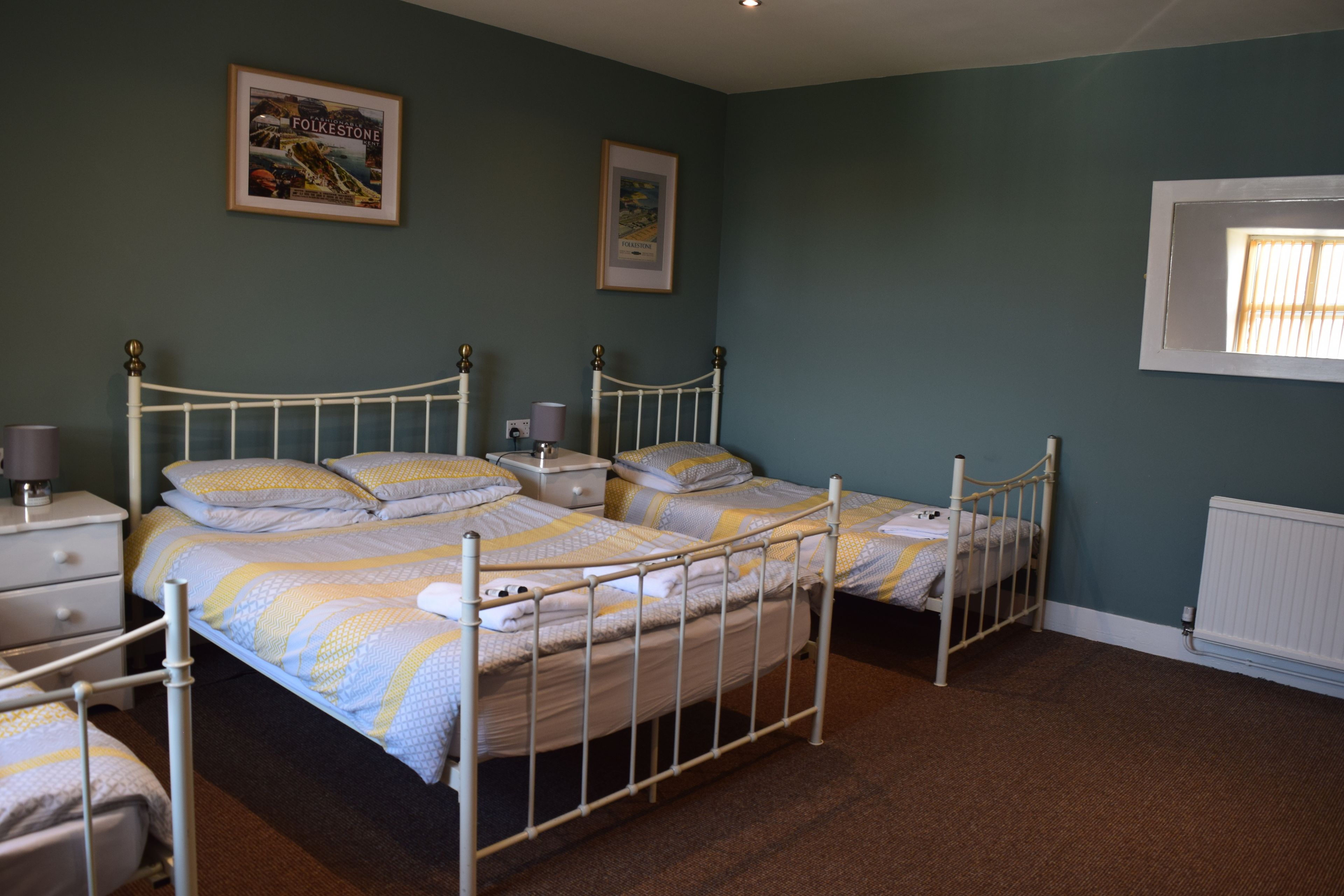 A bedroom with two single beds, a nightstand, a dresser, and a framed picture on the wall.
