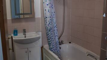 A bathroom with a sink, mirror, shower, and bathtub.