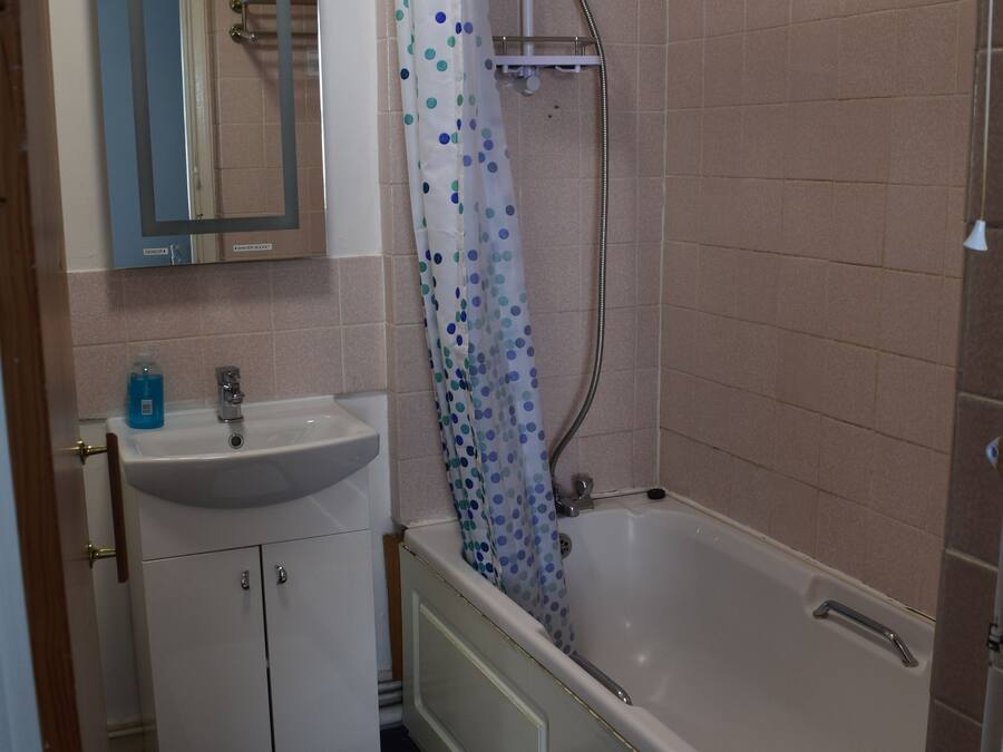 A bathroom with a sink, mirror, shower, and bathtub.